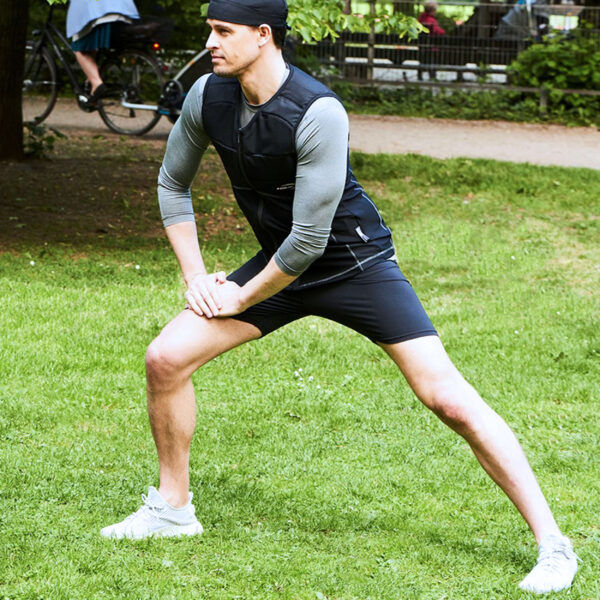 Man wearing cooling shirt from E.COOLINE in black and doing sports on grass